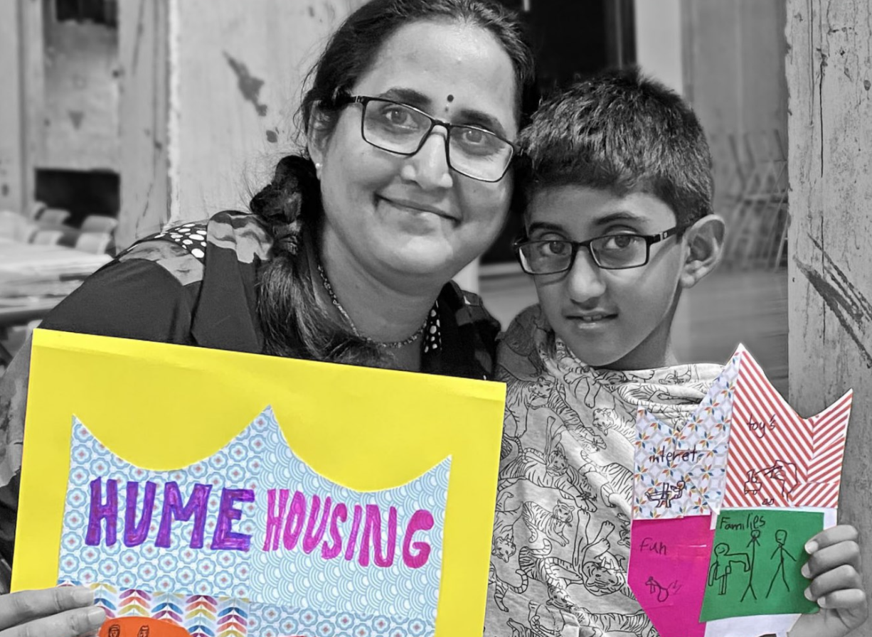 A Hume customer and her son hold up artworks in the shape of shields with the words "Hume Housing" on the front.